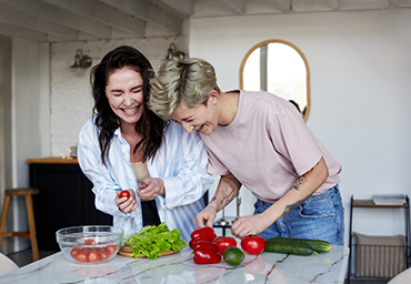 Deux femmes rient en coupant des légumes